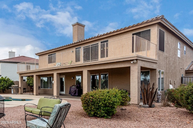 rear view of property with a fenced in pool, a balcony, and a patio area