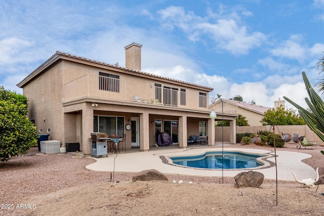 back of house with a fenced in pool, a patio, and a balcony