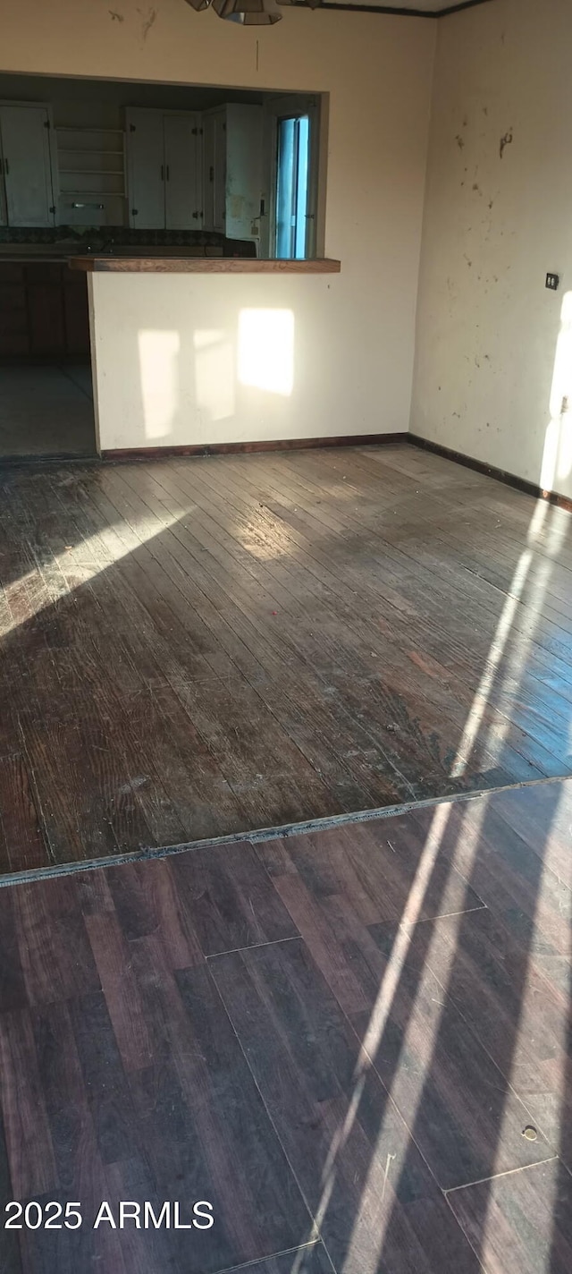 unfurnished living room featuring baseboards, electric panel, and hardwood / wood-style floors