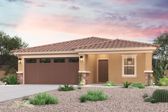 mediterranean / spanish house with a garage, driveway, a tile roof, and stucco siding