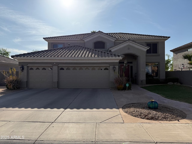 mediterranean / spanish-style home with driveway, stucco siding, a tile roof, and a garage