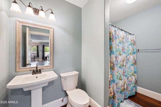 full bathroom with toilet, curtained shower, a sink, wood finished floors, and baseboards