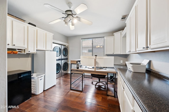 home office featuring washer and clothes dryer, stacked washer / drying machine, dark wood-style floors, visible vents, and ceiling fan