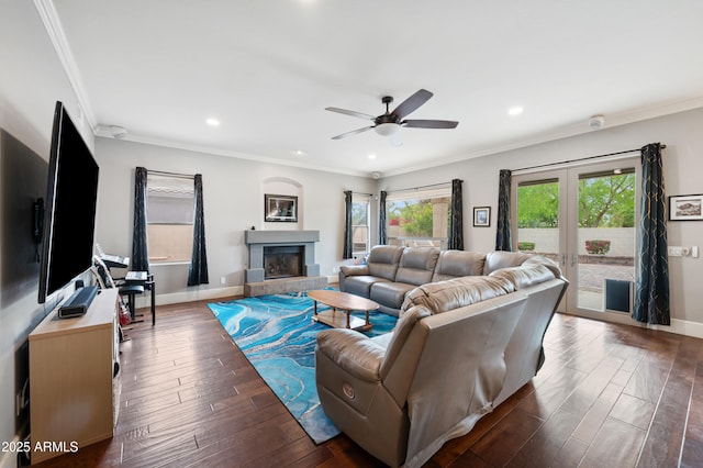 living room with a ceiling fan, crown molding, baseboards, and dark wood finished floors