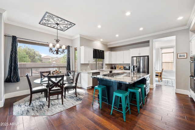 kitchen featuring white cabinetry, light stone countertops, dark wood finished floors, stainless steel appliances, and an inviting chandelier
