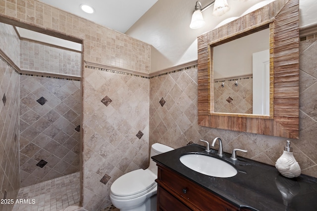 bathroom with toilet, vanity, tile walls, and a tile shower