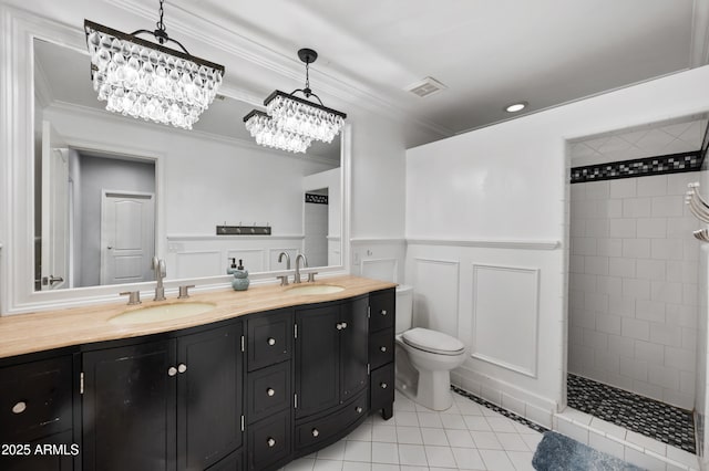bathroom with a wainscoted wall, a sink, double vanity, and crown molding