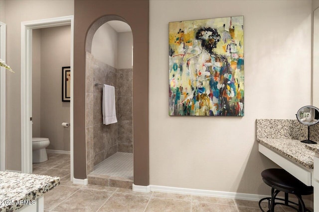 bathroom with vanity, tiled shower, tile patterned floors, and toilet