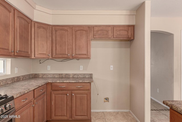 kitchen featuring light tile patterned floors and stainless steel gas range oven