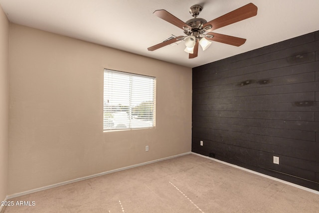 carpeted spare room featuring ceiling fan and wooden walls