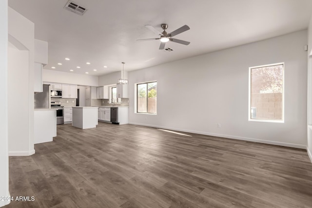 unfurnished living room with sink, dark wood-type flooring, and ceiling fan with notable chandelier