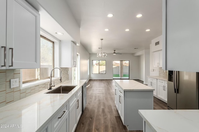 kitchen featuring white cabinets, sink, hanging light fixtures, ceiling fan, and a kitchen island