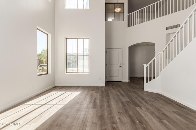 interior space with dark hardwood / wood-style flooring and a towering ceiling