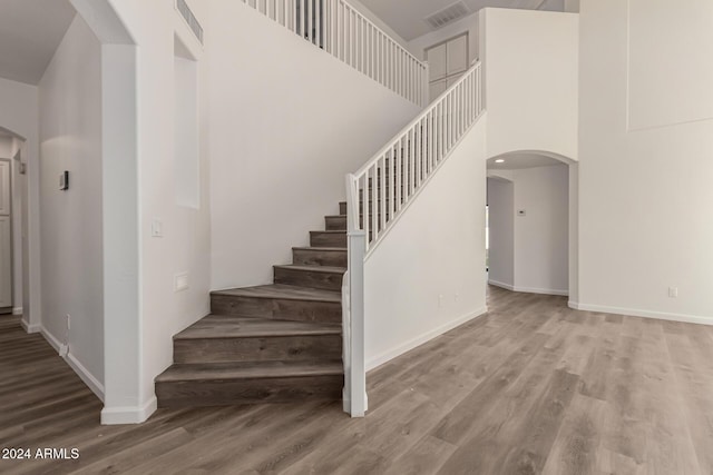 stairway with hardwood / wood-style flooring and a towering ceiling