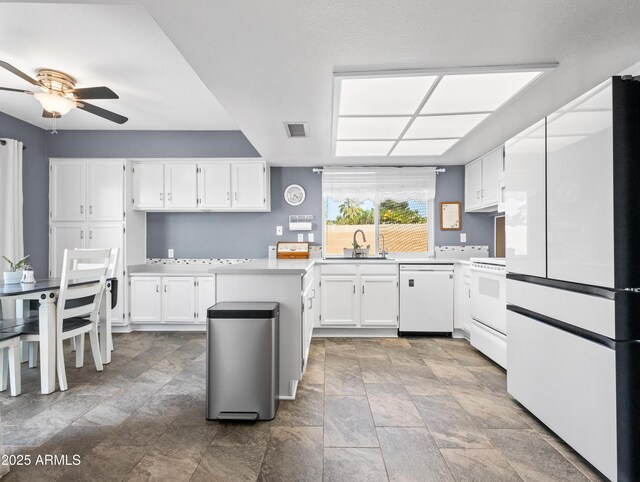 7726 W Cameron Dr, Peoria, AZ 85345 - kitchen with white appliances, a ceiling fan, stone finish flooring, visible vents, and a sink