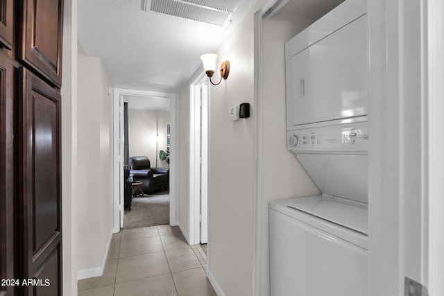 laundry area with light tile patterned flooring and stacked washer / dryer