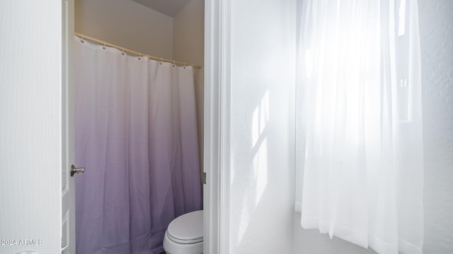 bathroom featuring toilet and curtained shower