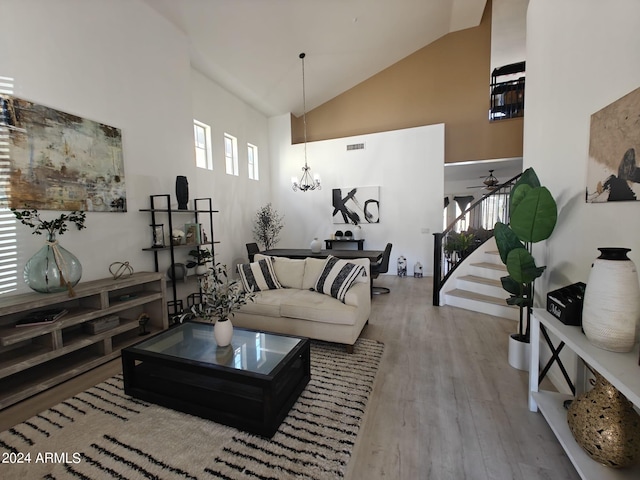 living room with high vaulted ceiling, hardwood / wood-style flooring, and ceiling fan with notable chandelier