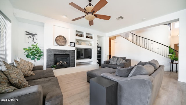 living room featuring ceiling fan, light wood-type flooring, and built in shelves