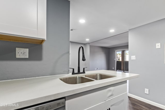 kitchen with a sink, light countertops, dark wood-style flooring, and white cabinetry