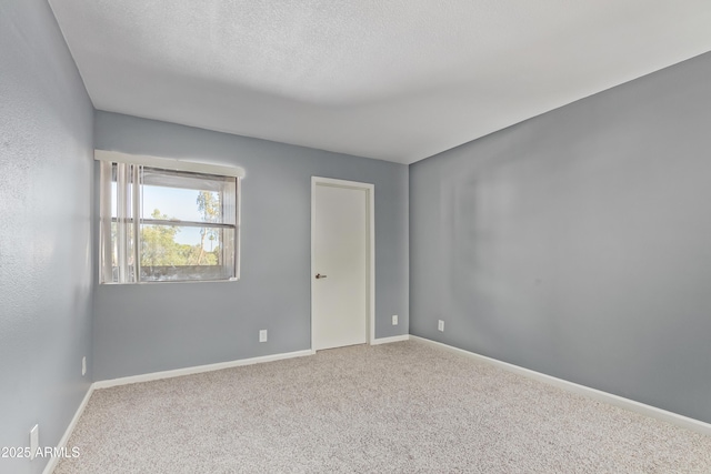 carpeted empty room featuring baseboards