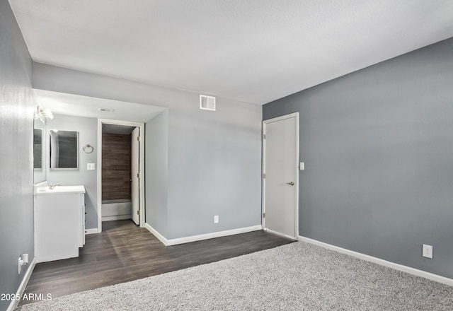 interior space with baseboards, visible vents, dark wood finished floors, and dark carpet
