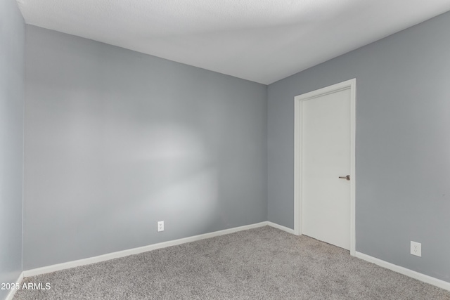 spare room with baseboards and carpet