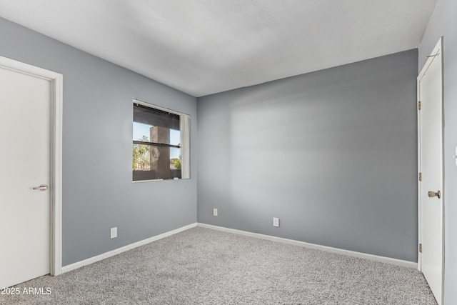 carpeted empty room featuring baseboards