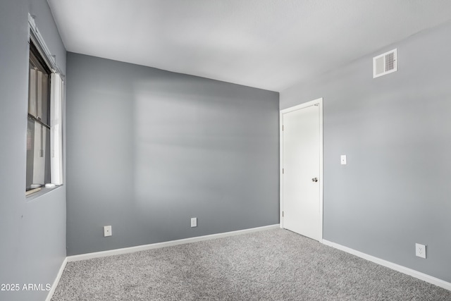 spare room with carpet flooring, baseboards, and visible vents