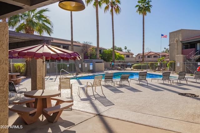 community pool with a patio and fence