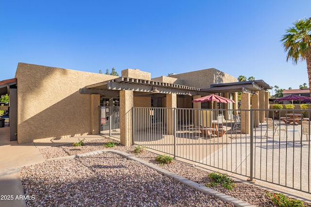 pueblo-style house featuring fence, a patio, stucco siding, and a pergola