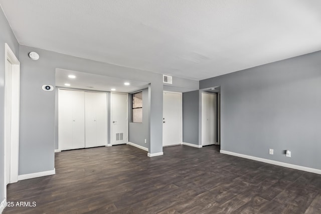interior space featuring baseboards, dark wood-type flooring, recessed lighting, and visible vents