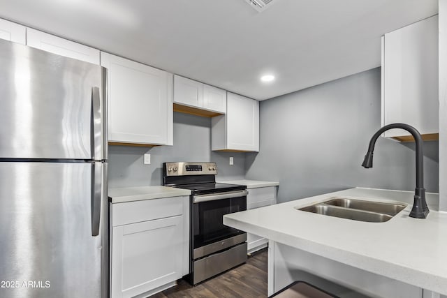 kitchen with dark wood-style floors, light countertops, white cabinetry, a sink, and appliances with stainless steel finishes