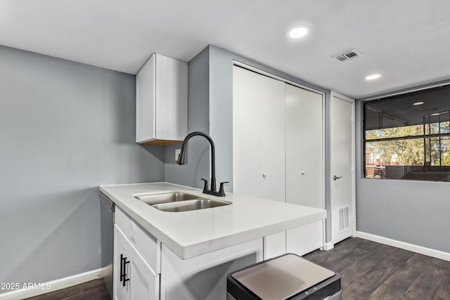 kitchen featuring dark wood-style flooring, visible vents, a sink, baseboards, and white cabinets