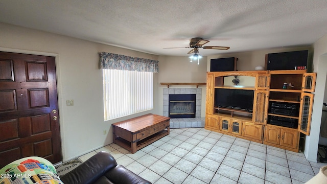 tiled living room with a textured ceiling, a fireplace, and ceiling fan