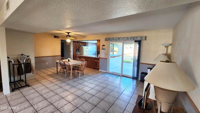 dining space featuring ceiling fan, ornamental molding, a textured ceiling, and light tile patterned flooring