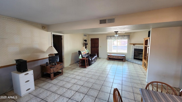 tiled living room with ceiling fan and a tiled fireplace