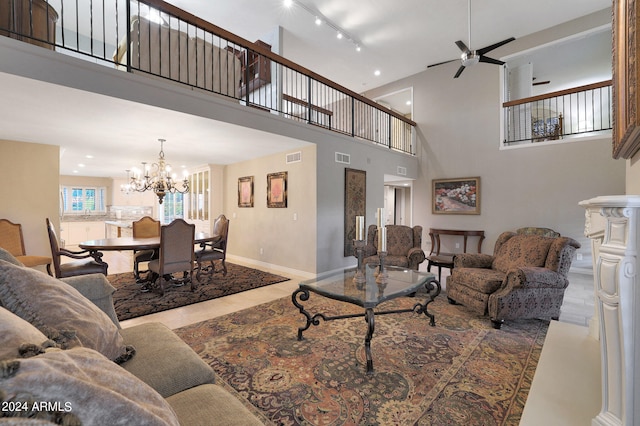 tiled living room featuring a high ceiling and ceiling fan with notable chandelier