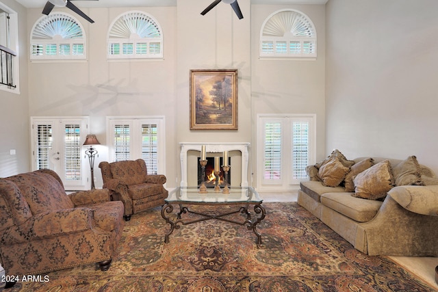 living room featuring a high ceiling, a high end fireplace, plenty of natural light, and french doors