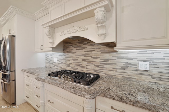 kitchen featuring light stone counters, custom exhaust hood, backsplash, white cabinetry, and appliances with stainless steel finishes