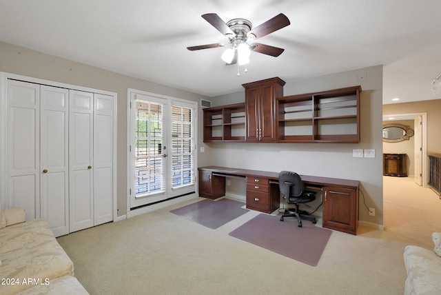 office area featuring light carpet, ceiling fan, and built in desk