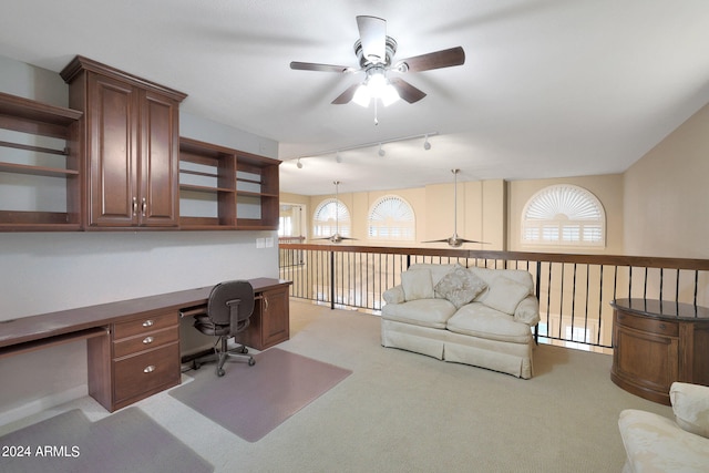 office featuring light carpet, ceiling fan, rail lighting, and built in desk