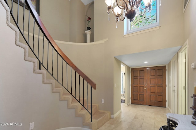 foyer featuring light tile patterned flooring, a towering ceiling, and a chandelier