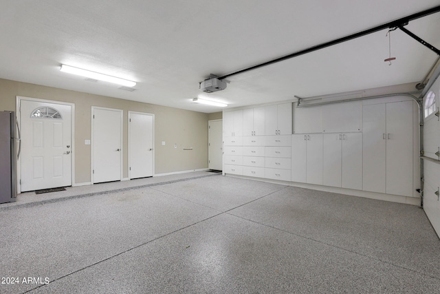 garage with a garage door opener and stainless steel refrigerator