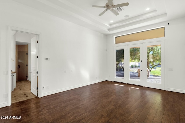 spare room with french doors, dark hardwood / wood-style floors, a raised ceiling, and ceiling fan