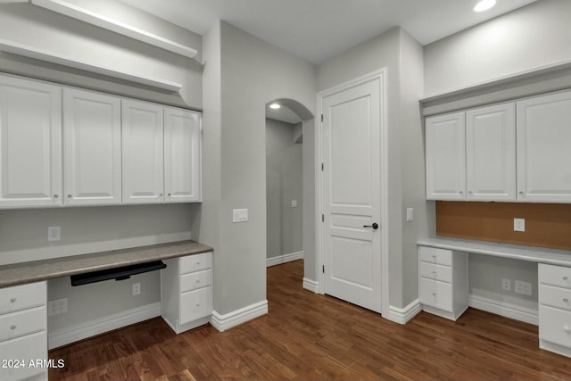 unfurnished office featuring built in desk and dark wood-type flooring