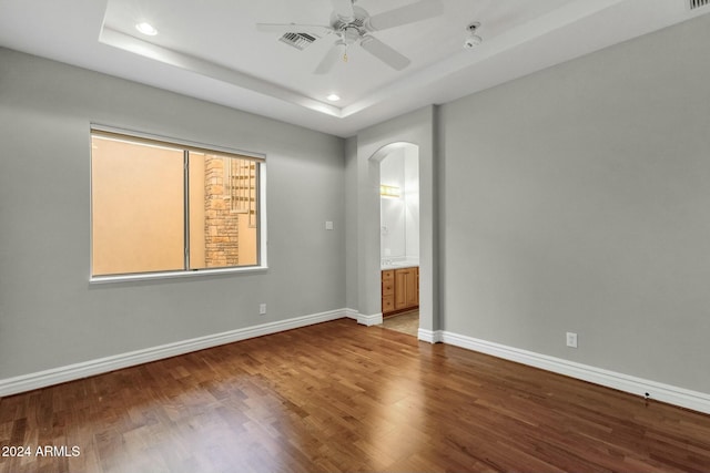 spare room featuring hardwood / wood-style flooring, a raised ceiling, and ceiling fan