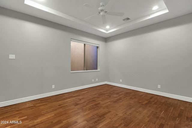 spare room with hardwood / wood-style flooring, ceiling fan, and a tray ceiling