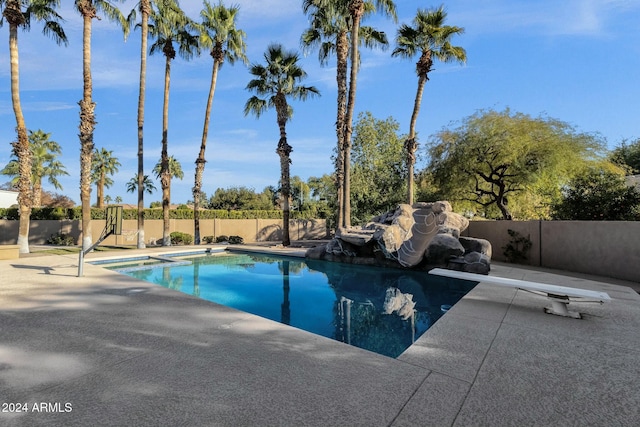 view of swimming pool featuring a patio and a diving board