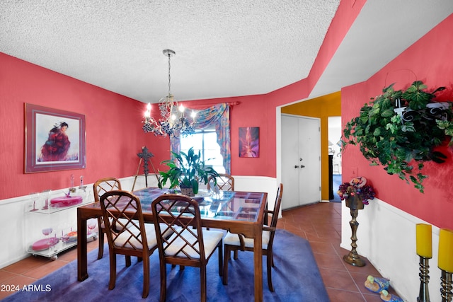 dining area featuring a textured ceiling, dark tile patterned flooring, and a chandelier